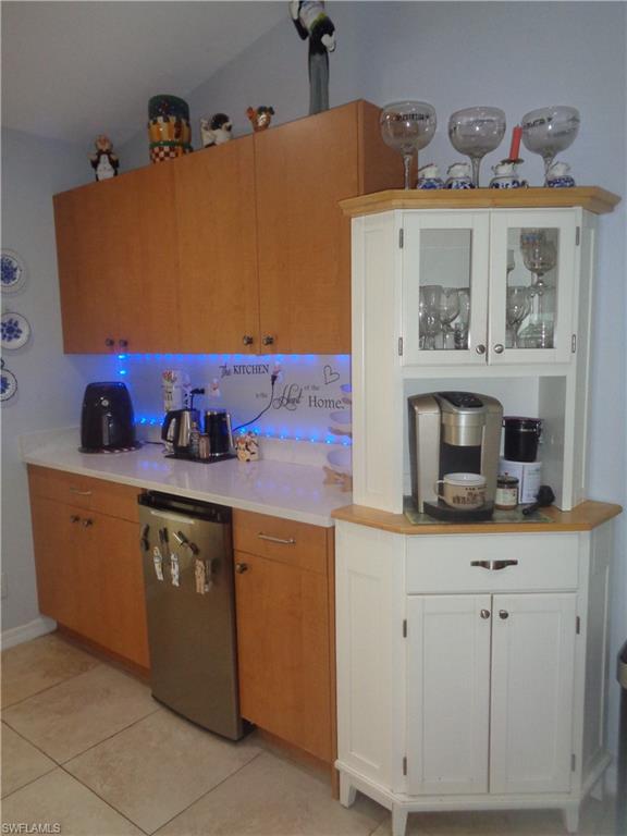 Kitchen featuring white cabinets, dishwasher, light tile patterned flooring, and glass insert cabinets