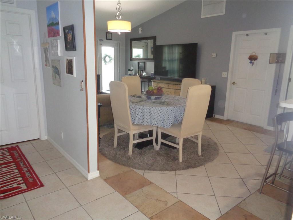 Dining area featuring light tile patterned floors and vaulted ceiling