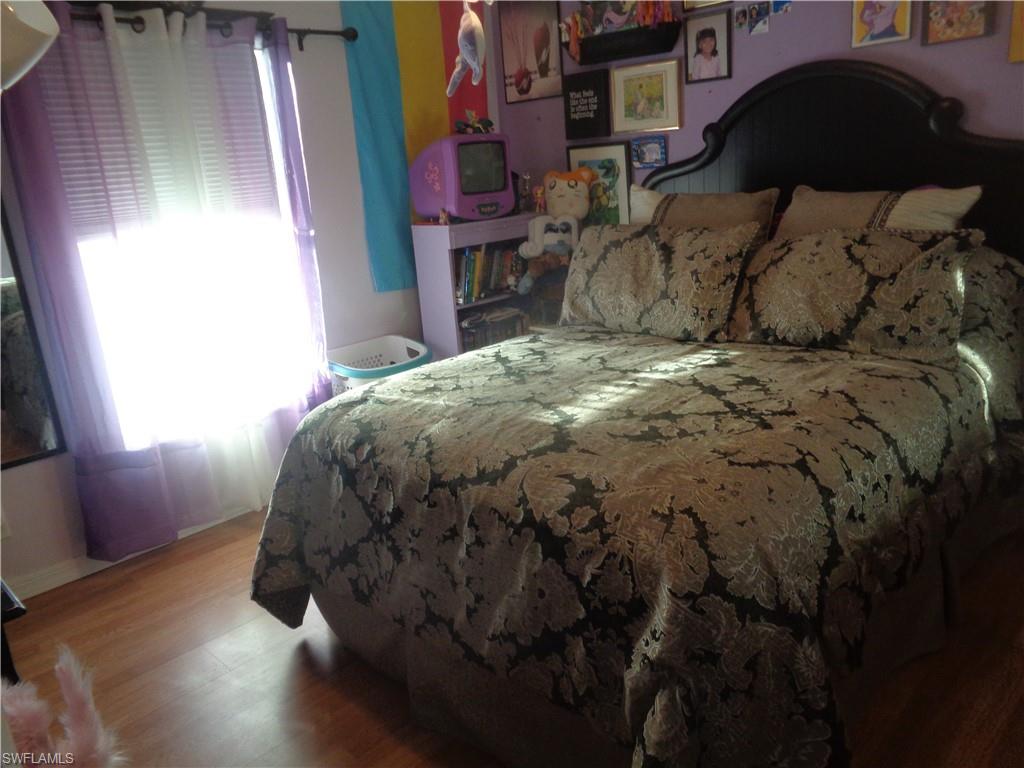 Bedroom with wood finished floors and multiple windows