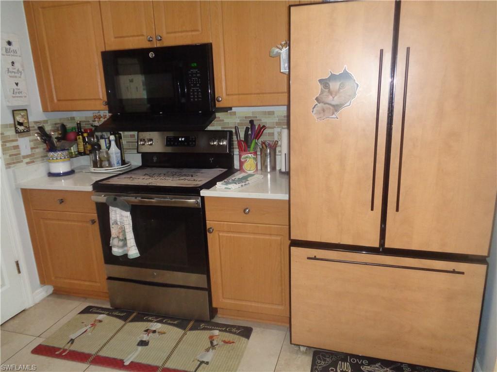 Kitchen featuring stainless steel electric range, black microwave, light countertops, and paneled refrigerator