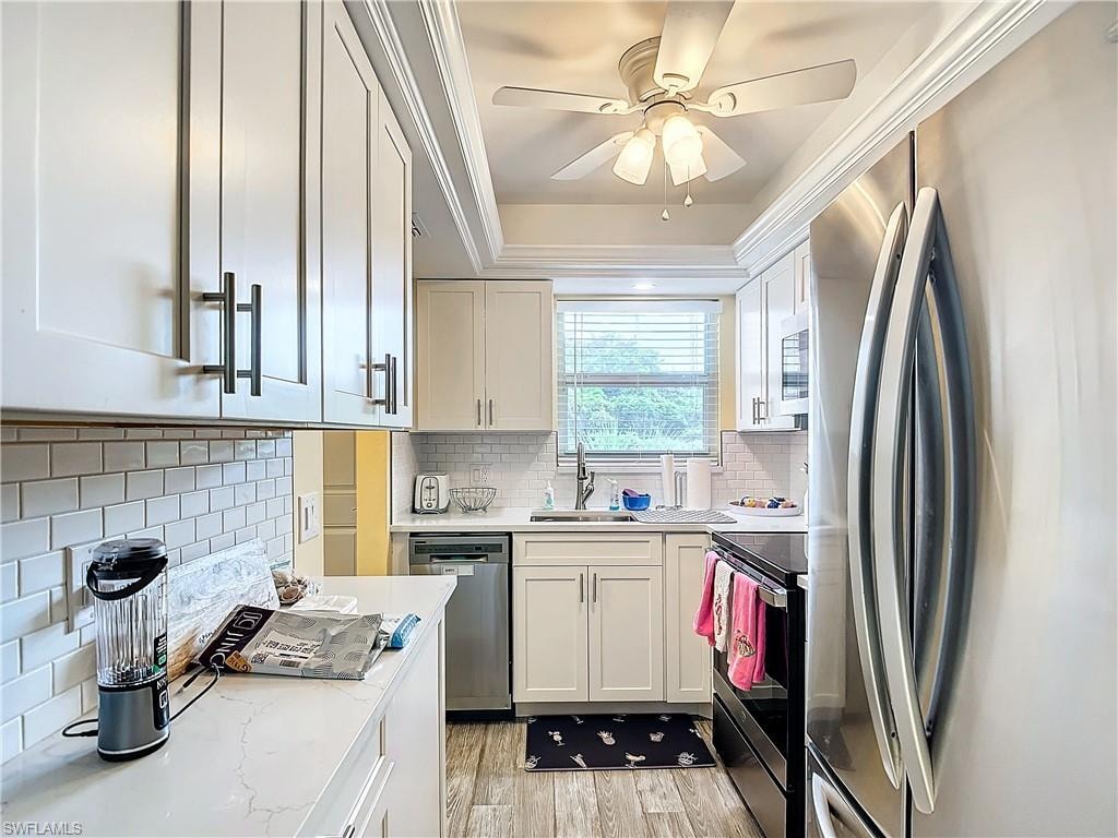 Kitchen featuring ceiling fan, decorative backsplash, white cabinetry, appliances with stainless steel finishes, and light hardwood / wood-style floors
