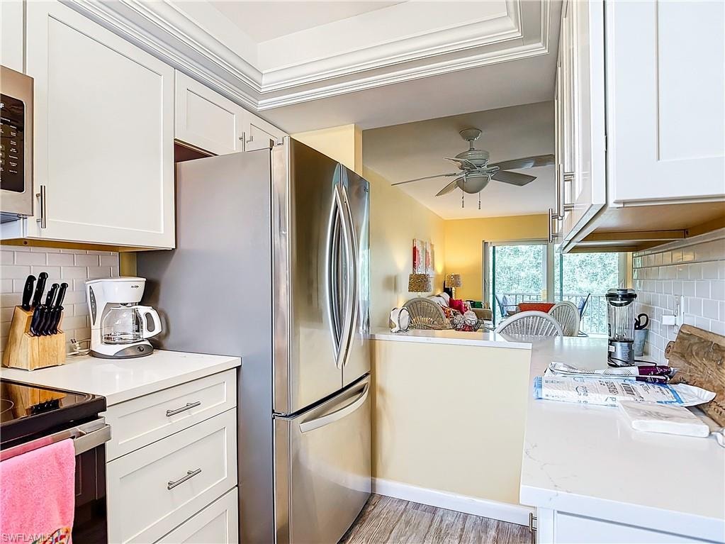 Kitchen with light wood-type flooring, tasteful backsplash, ceiling fan, and white cabinets