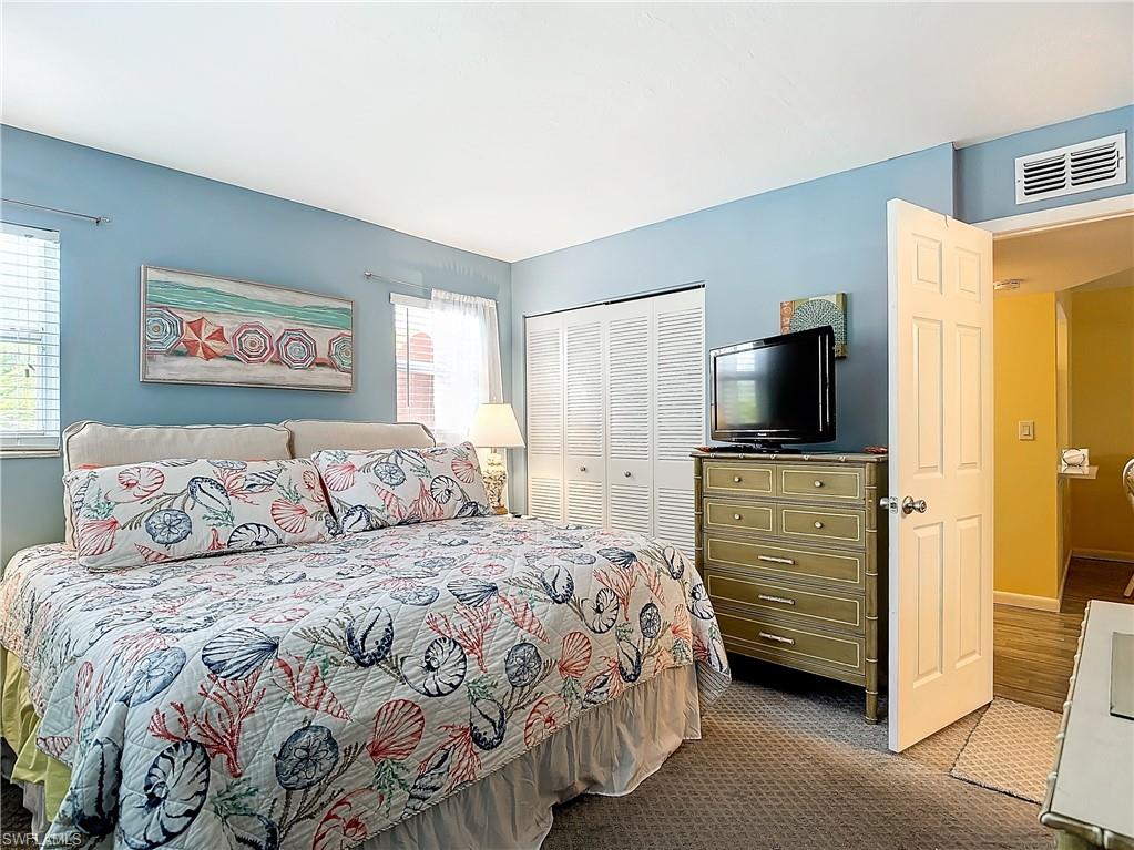 Carpeted bedroom with a closet and multiple windows