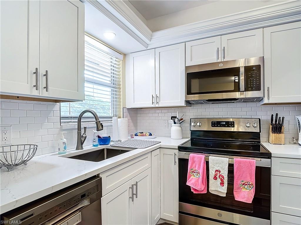 Kitchen with sink, stainless steel appliances, white cabinetry, and tasteful backsplash
