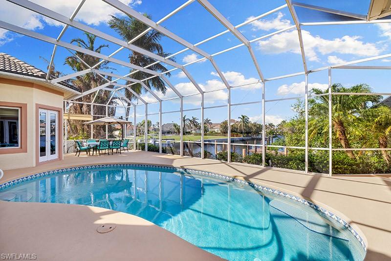 View of pool with glass enclosure, a patio area, and a water view