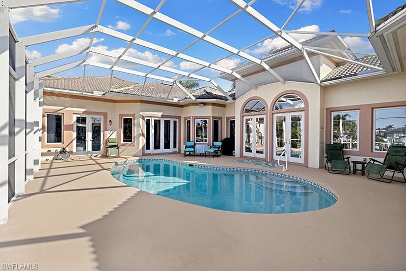 View of swimming pool featuring french doors, glass enclosure, and a patio
