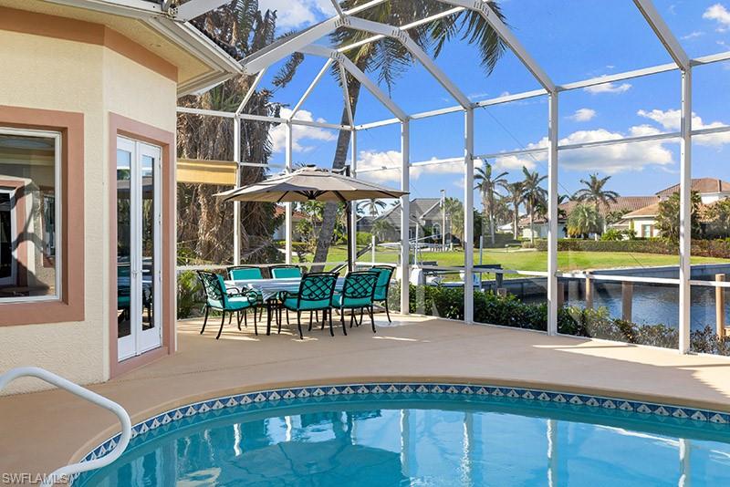 View of pool featuring glass enclosure and a patio