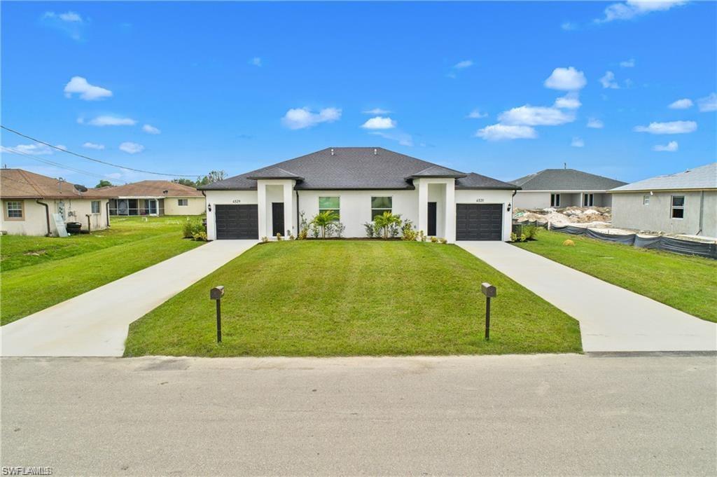 Prairie-style home featuring driveway, a front lawn, stucco siding, and a garage