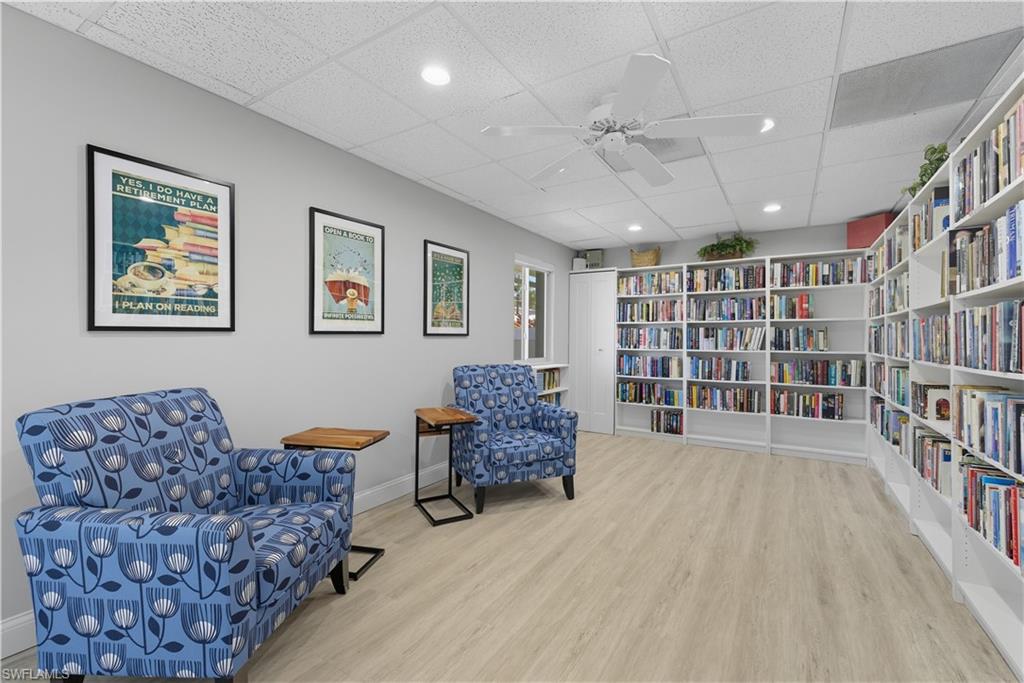 Living area featuring wall of books, recessed lighting, a paneled ceiling, light wood-style flooring, and ceiling fan