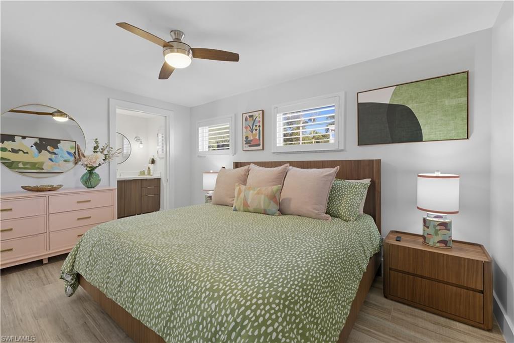 Bedroom with light wood-style flooring, a ceiling fan, and ensuite bathroom