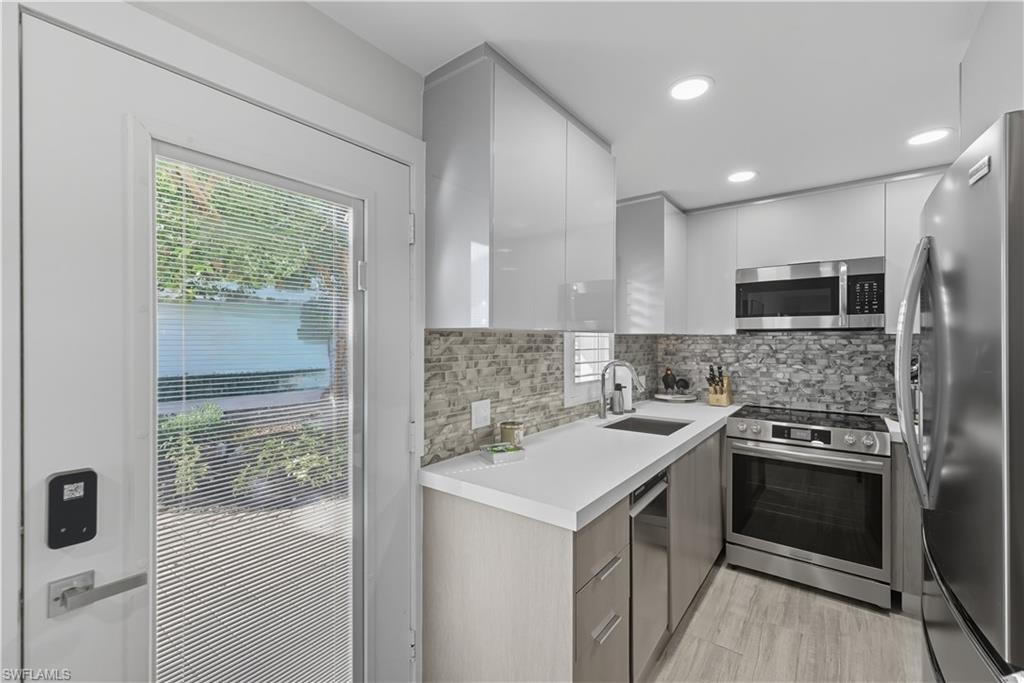 Kitchen with modern cabinets, light countertops, tasteful backsplash, appliances with stainless steel finishes, and white cabinets