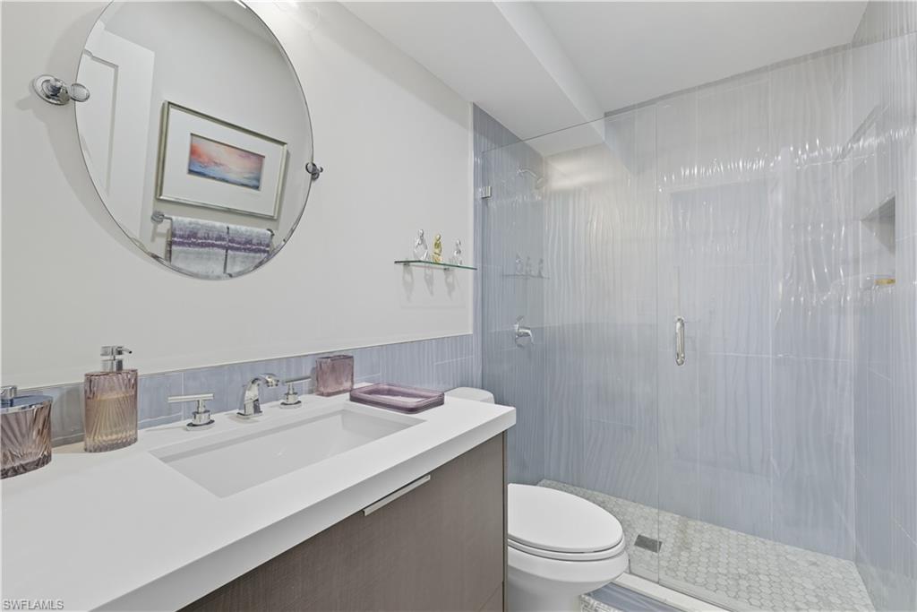Full bathroom with a stall shower, vanity, and wainscoting