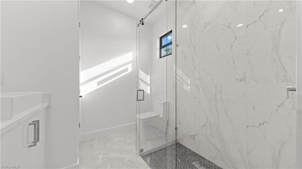 Full bath with a marble finish shower, light marble finish flooring, and vanity