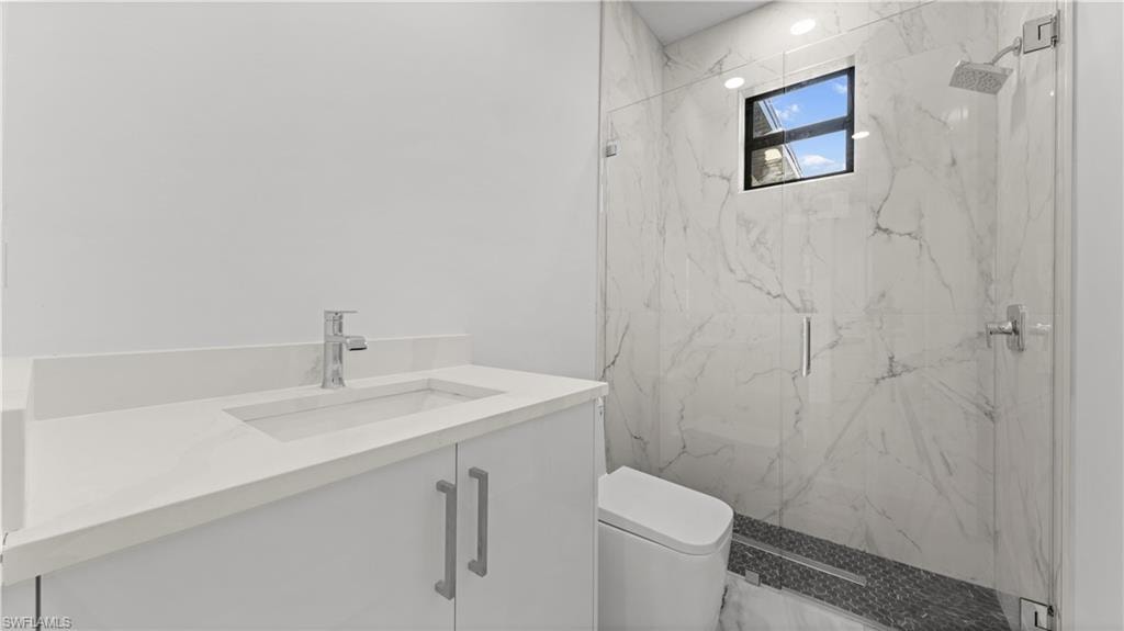 Full bath featuring vanity and a marble finish shower