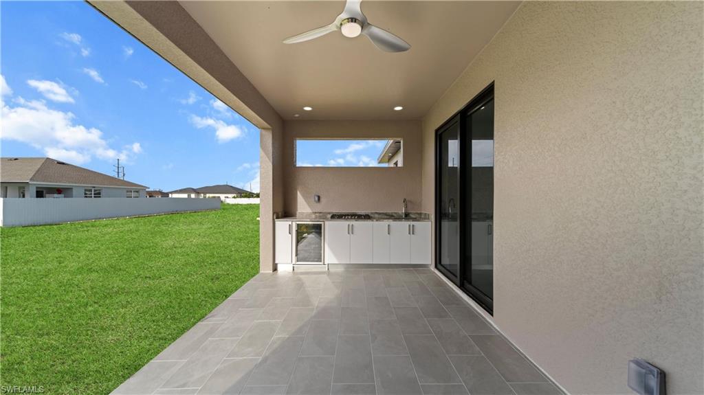 View of patio with ceiling fan, an outdoor kitchen, and beverage cooler
