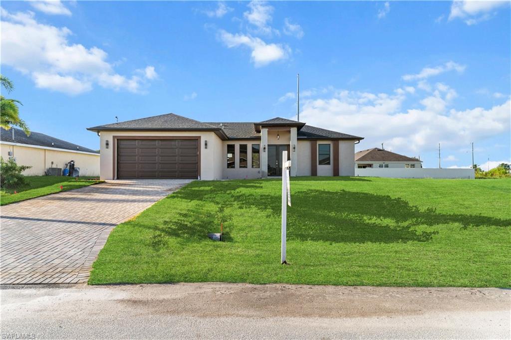 Prairie-style home with decorative driveway, a front yard, stucco siding, and an attached garage