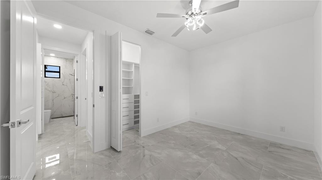 Unfurnished bedroom with light marble finish floors, a walk in closet, and ceiling fan