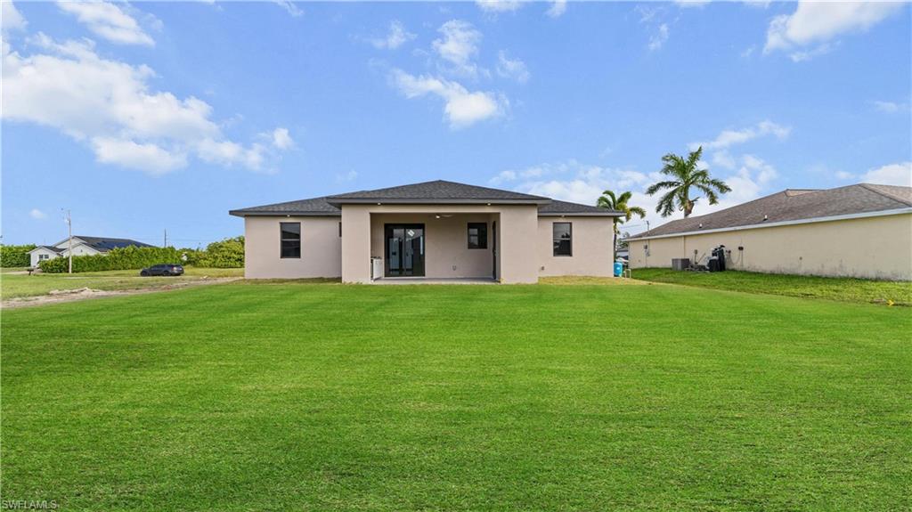 Back of property featuring a yard, a patio area, and stucco siding