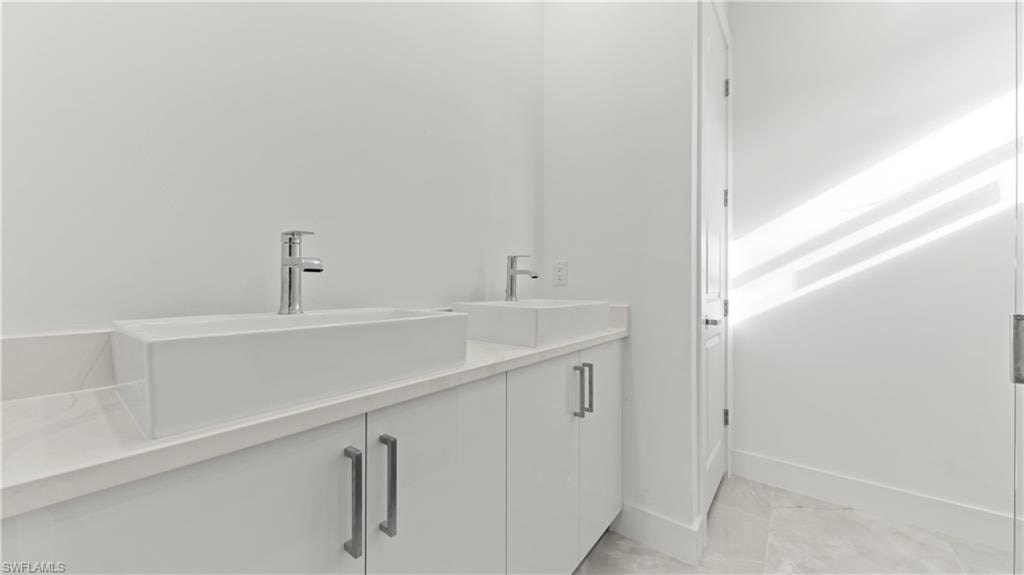 Bathroom featuring double vanity and light tile patterned floors