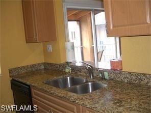 Kitchen featuring dishwasher, light stone countertops, and sink