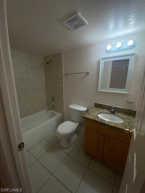 Full bathroom featuring tile patterned flooring, a textured ceiling, toilet, vanity, and shower / bathing tub combination