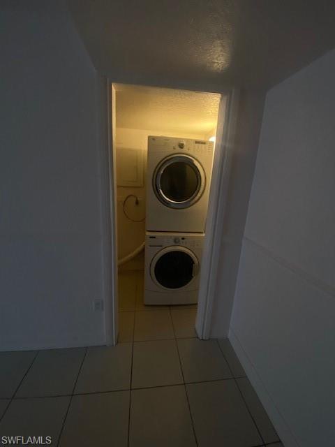 Washroom with light tile patterned flooring and stacked washer and dryer