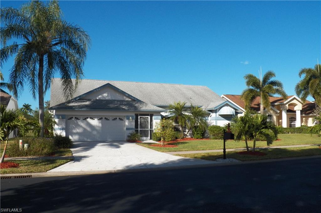 View of front of home with driveway, a front lawn, and a garage