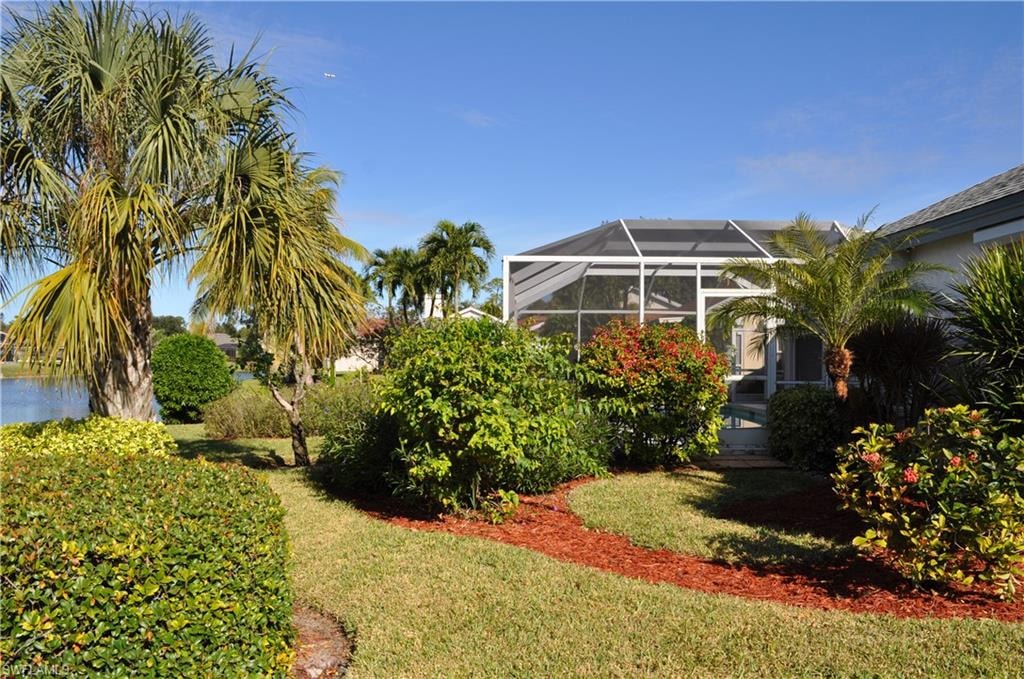 View of grassy yard featuring glass enclosure and a sunroom