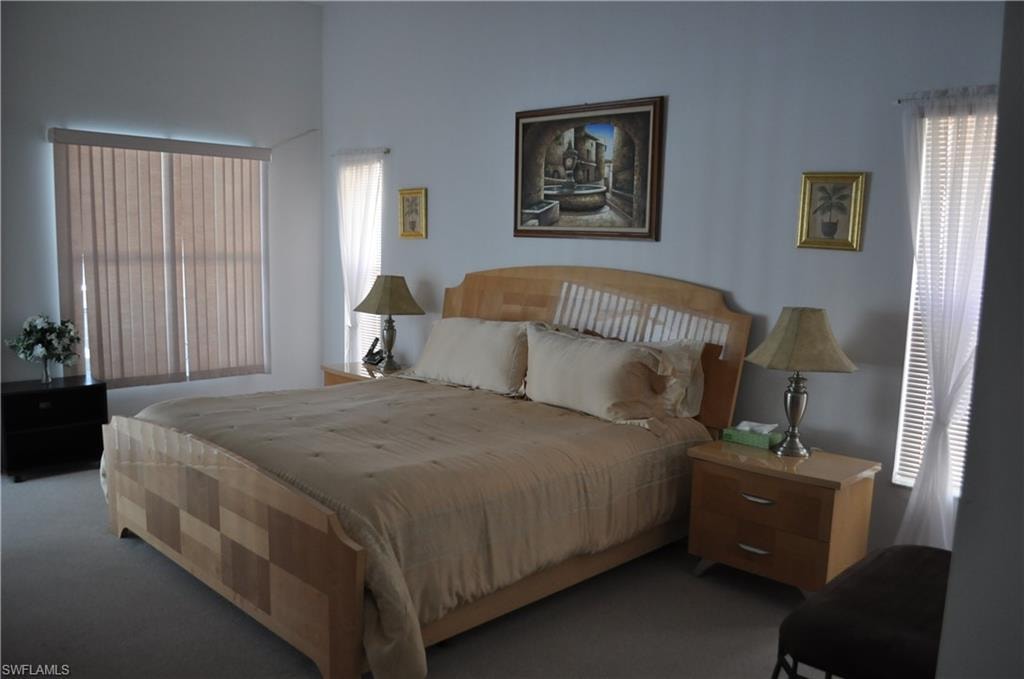 Bedroom featuring dark carpet and multiple windows