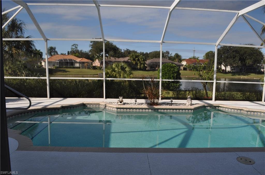 Outdoor pool with a sunroom, a water view, and glass enclosure
