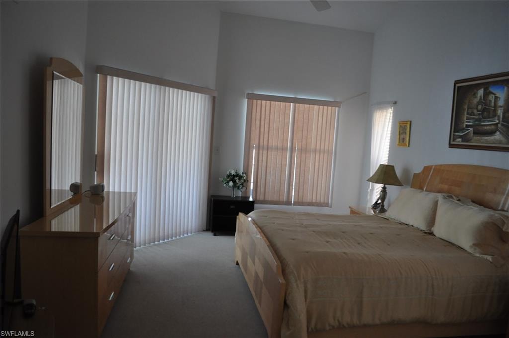 Bedroom featuring carpet floors, ceiling fan, and a towering ceiling