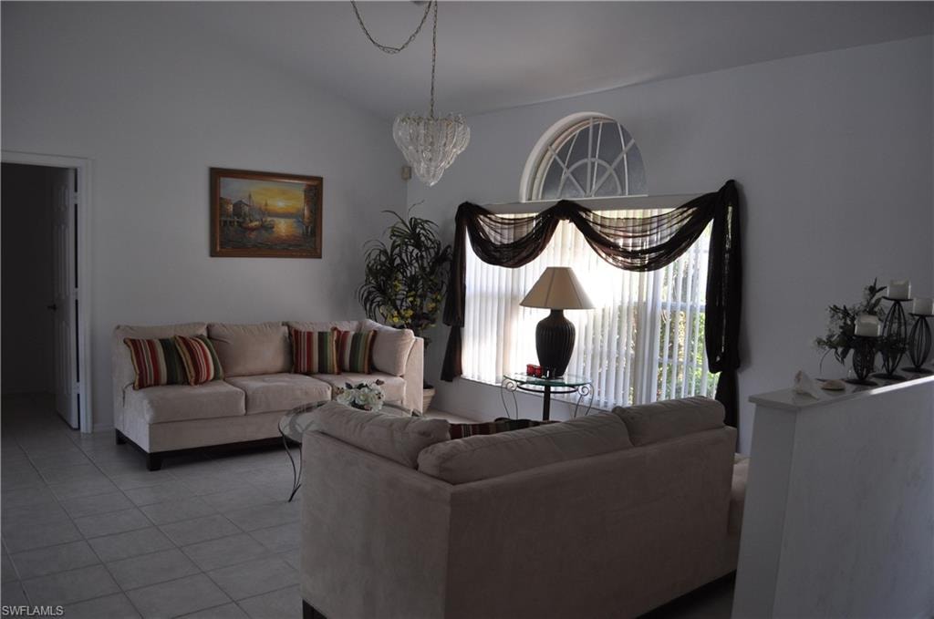Living area with tile patterned flooring, vaulted ceiling, and a chandelier