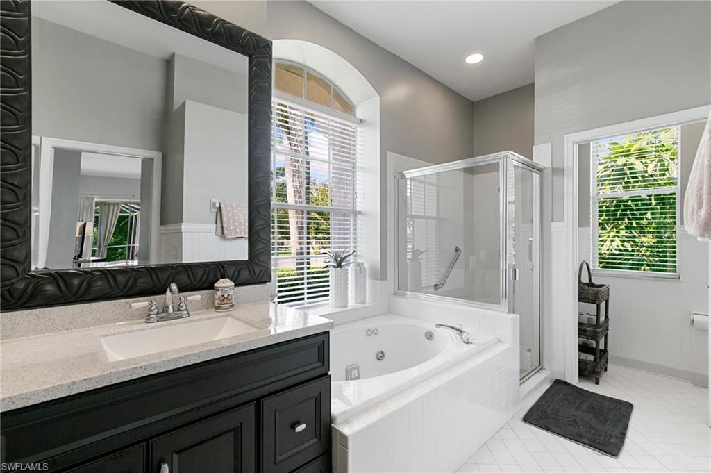 Bathroom featuring plus walk in shower, vanity, and tile patterned flooring
