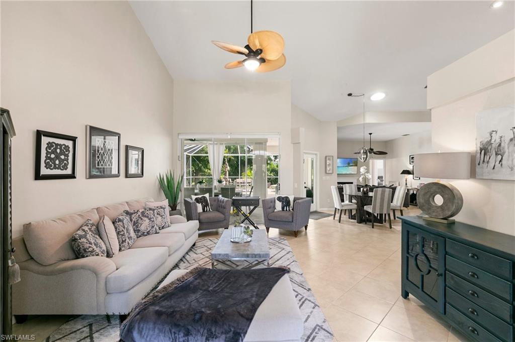 Living room with ceiling fan, high vaulted ceiling, and light tile patterned floors