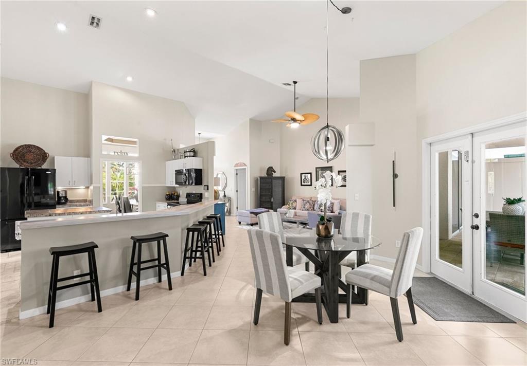 Tiled dining room with high vaulted ceiling and ceiling fan