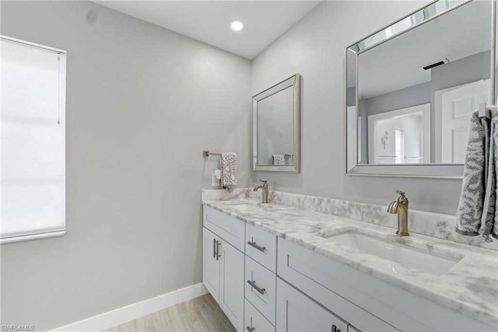 Full bath with double vanity, light wood-style flooring, and recessed lighting
