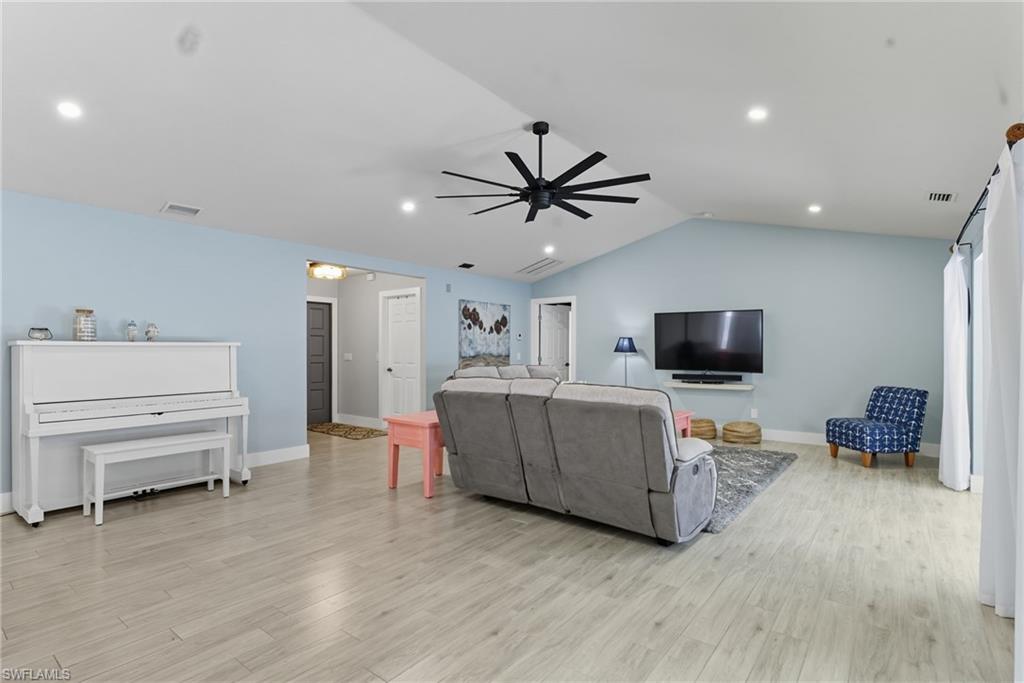 Living room with lofted ceiling, light wood-style floors, ceiling fan, and recessed lighting