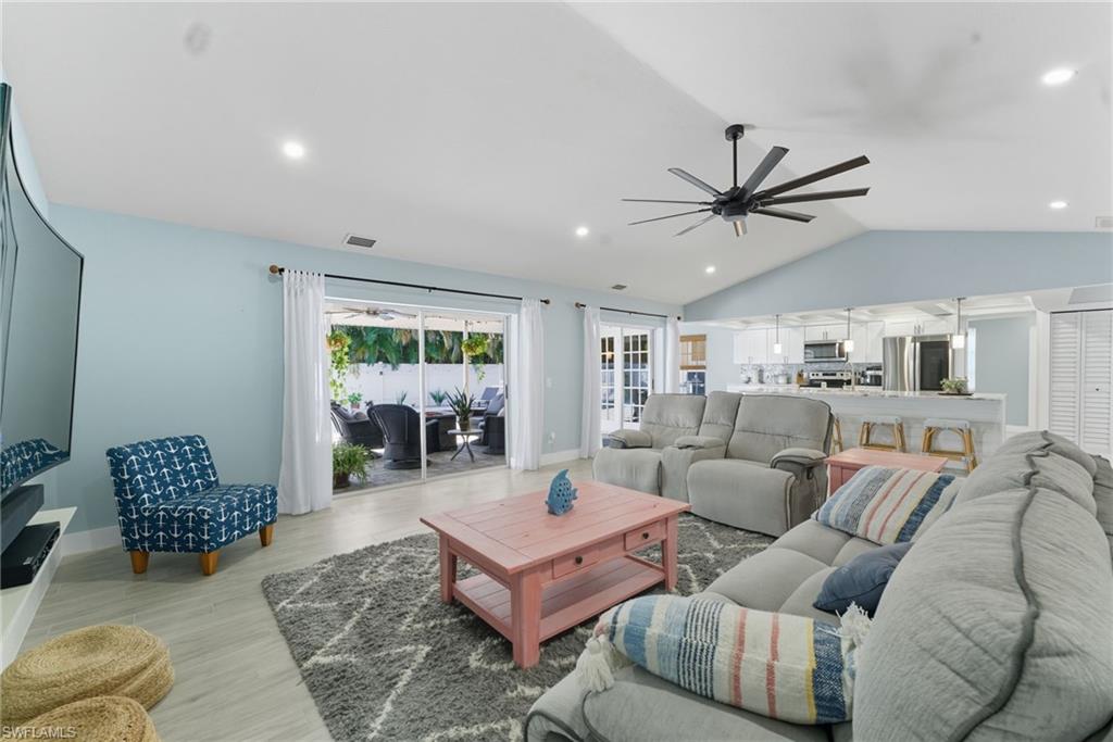 Living room featuring lofted ceiling, recessed lighting, light wood-style flooring, and a ceiling fan