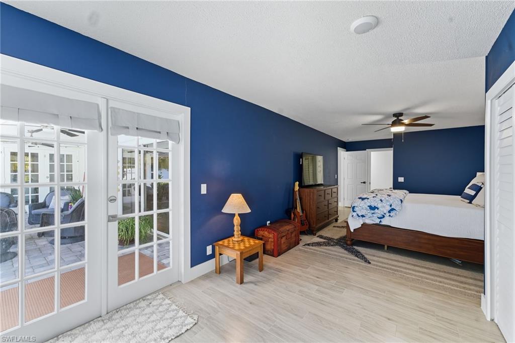 Bedroom featuring light wood-style flooring, access to outside, ceiling fan, and a textured ceiling