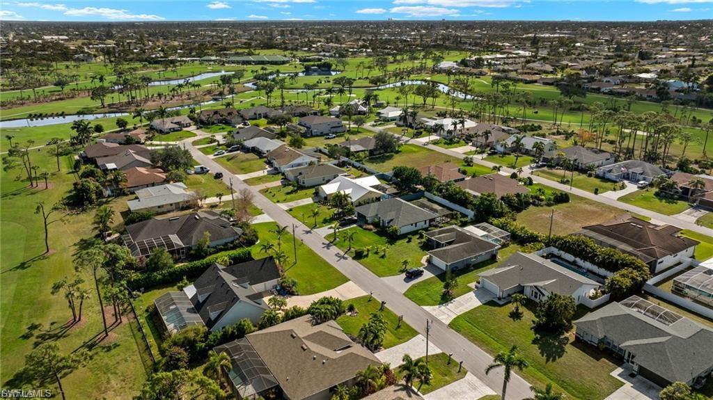 Aerial view of property's location featuring a large body of water, nearby suburban area, and a golf course