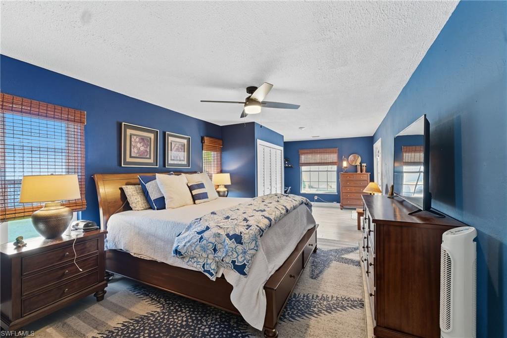 Bedroom featuring a closet, a textured ceiling, ceiling fan, and wood finished floors