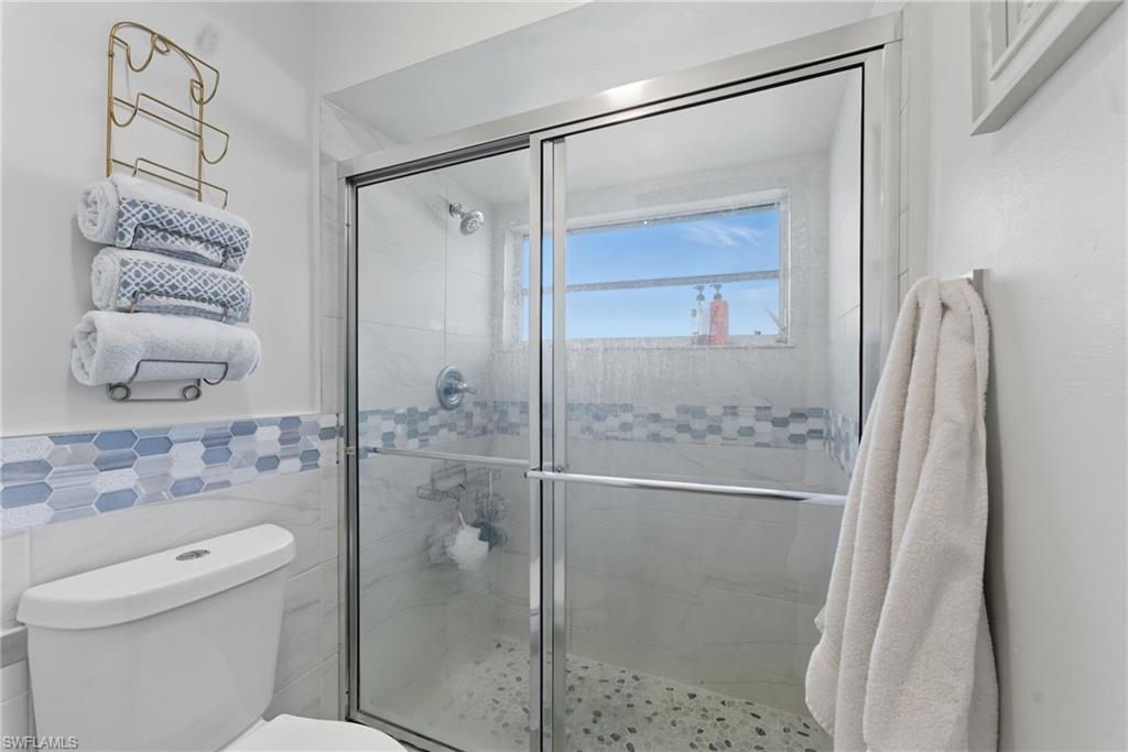Full bath with a shower stall and tile walls