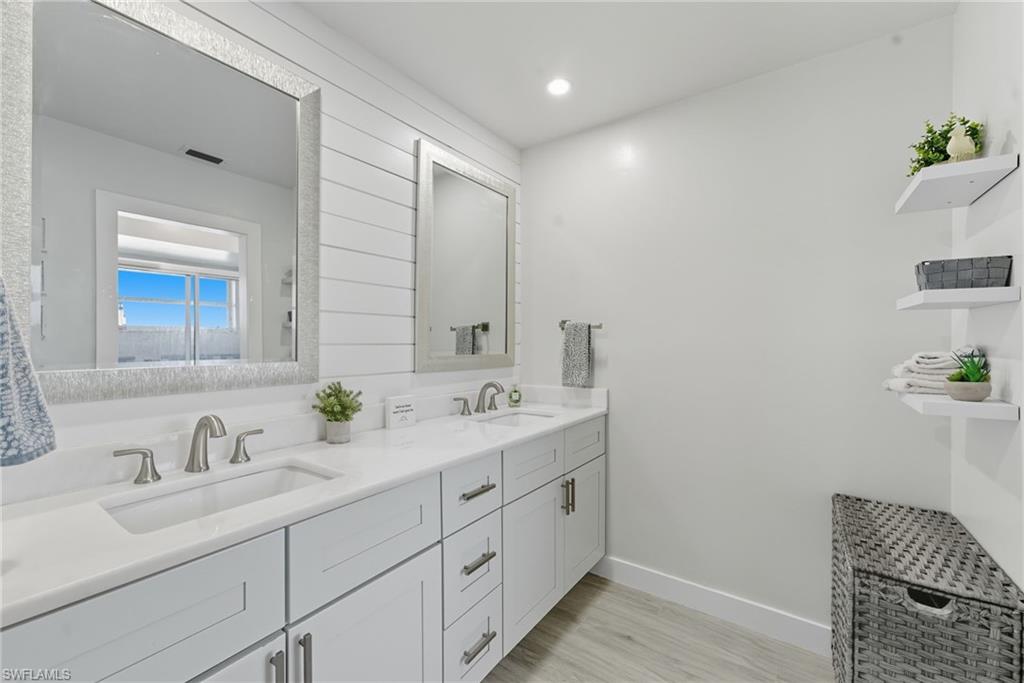 Bathroom with double vanity, light wood-style flooring, and recessed lighting