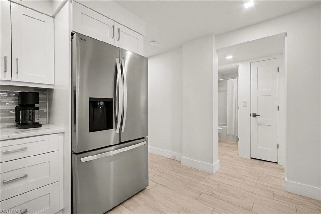 Stainless steel French door refrigerator with ice and water dispenser, framed by white shaker cabinetry