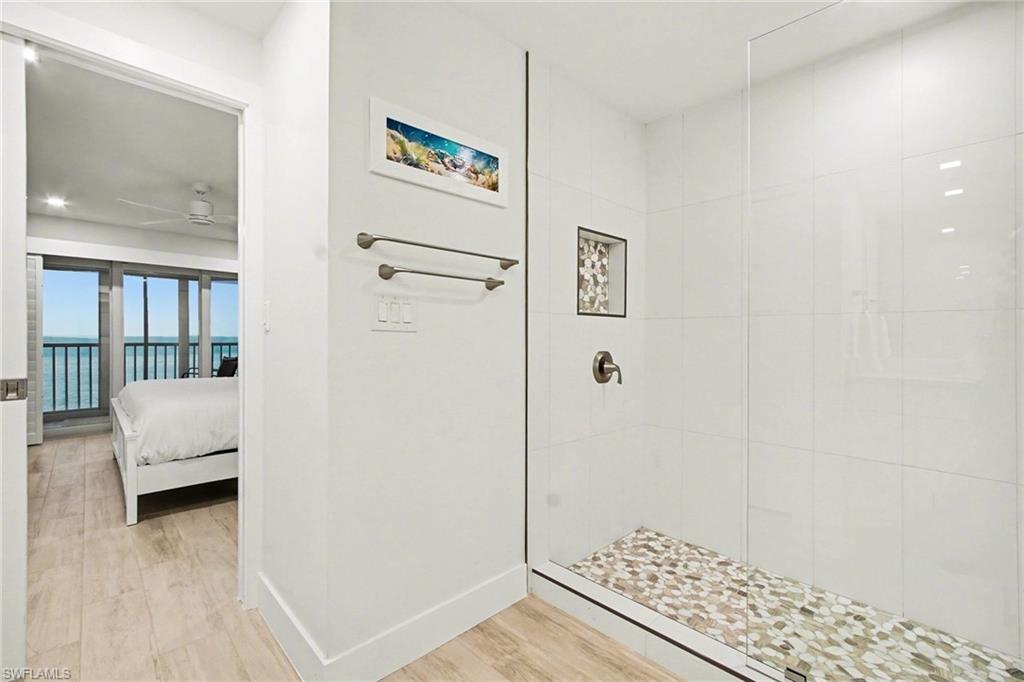 Glass-enclosed shower with white tiled walls and a natural stone pebble floor