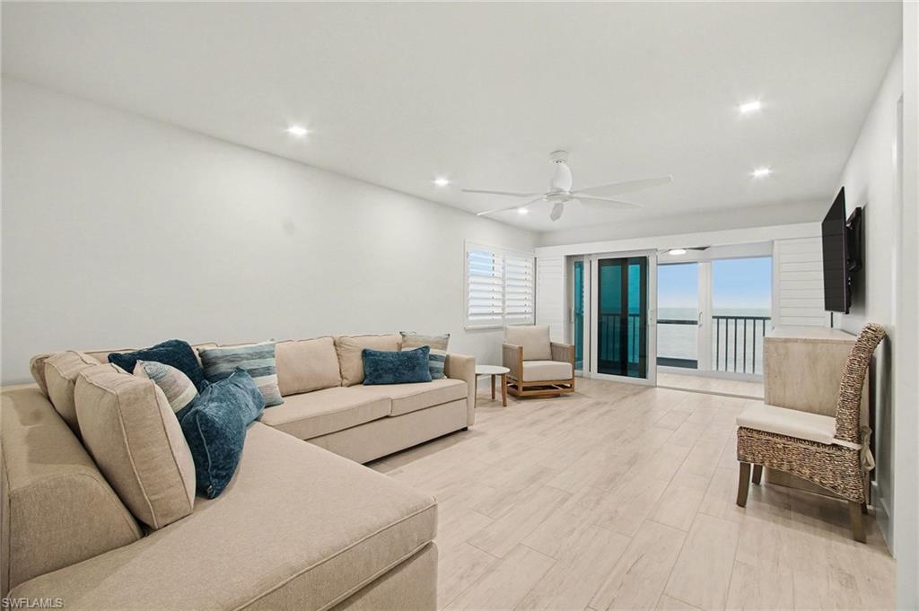 Spacious living area featuring light wood-finish flooring, recessed lighting, and a ceiling fan