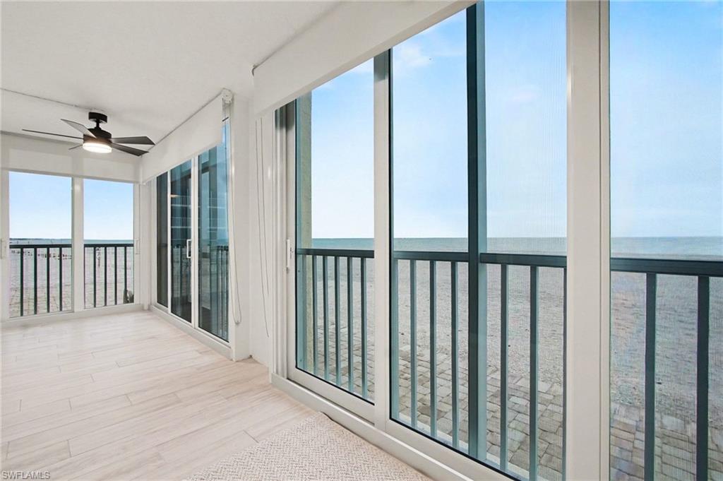 Expansive room featuring light wood-finish flooring and panoramic sliding glass doors opening to a balcony with metal railings