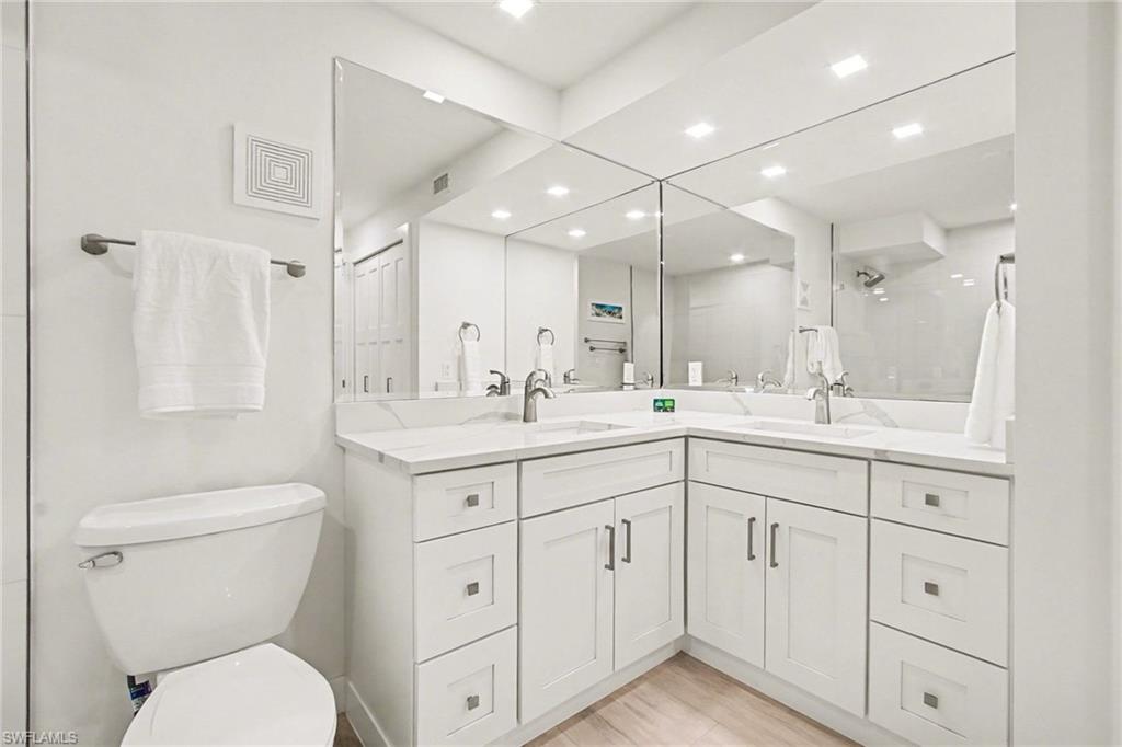 Bathroom featuring a dual vanity with white shaker cabinetry, light-toned countertops, and chrome fixtures