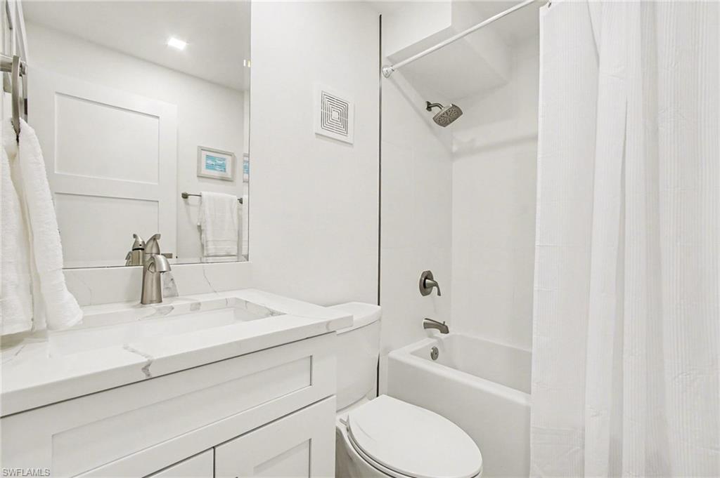 Bathroom featuring a white vanity with an integrated rectangular sink, a stone-finish countertop, and a brushed nickel faucet