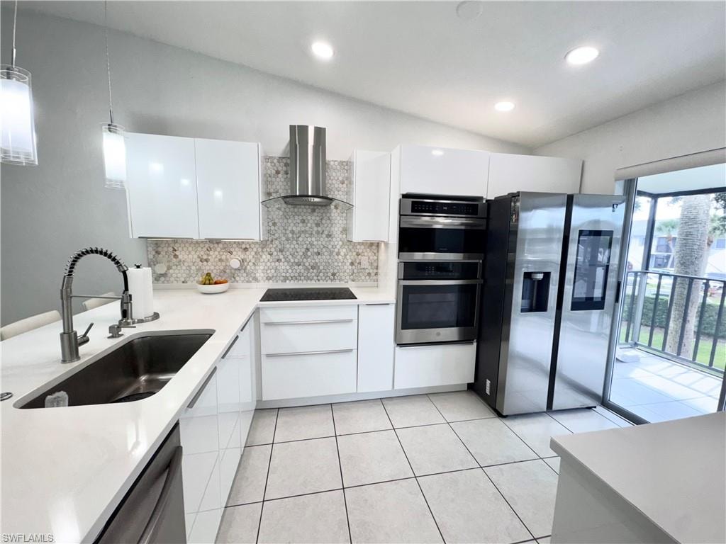 Kitchen featuring white cabinetry, stainless steel appliances, modern cabinets, hanging light fixtures, and backsplash